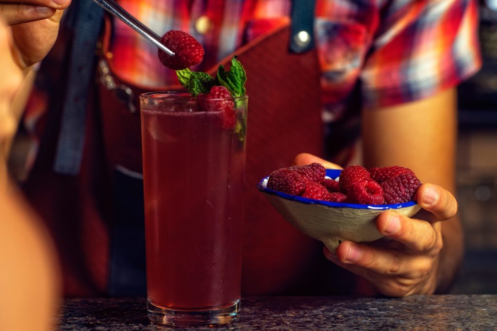 person putting strawberry in drinking glass